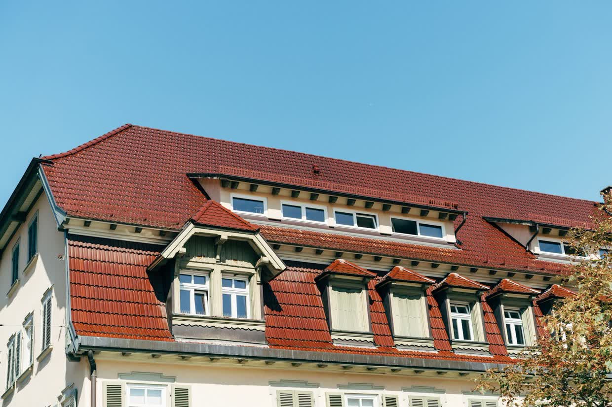 Rotes Ziegeldach eines Altbaus mit mehreren Gauben
